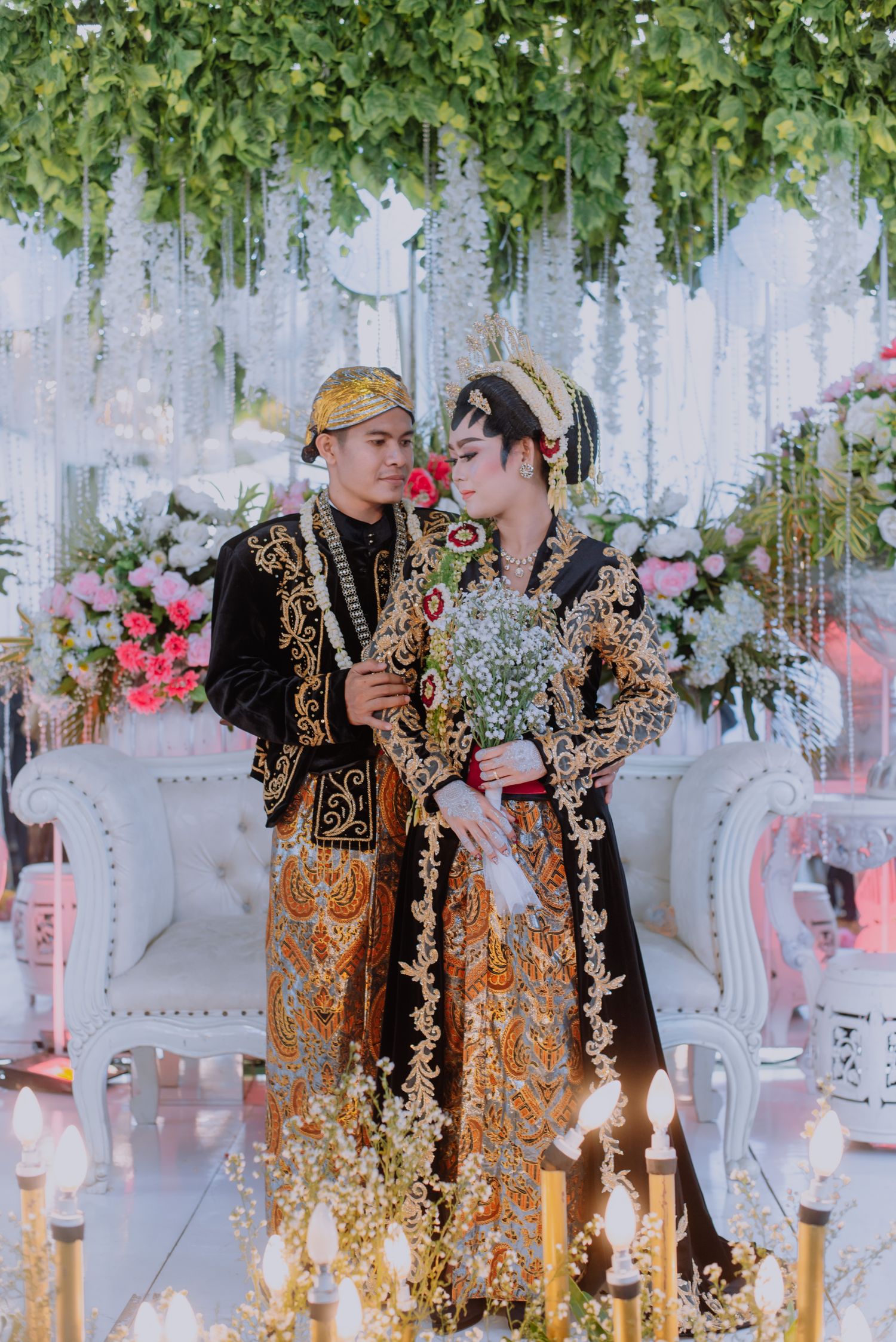 Pasangan pengantin dalam busana adat Jawa hitam dan emas