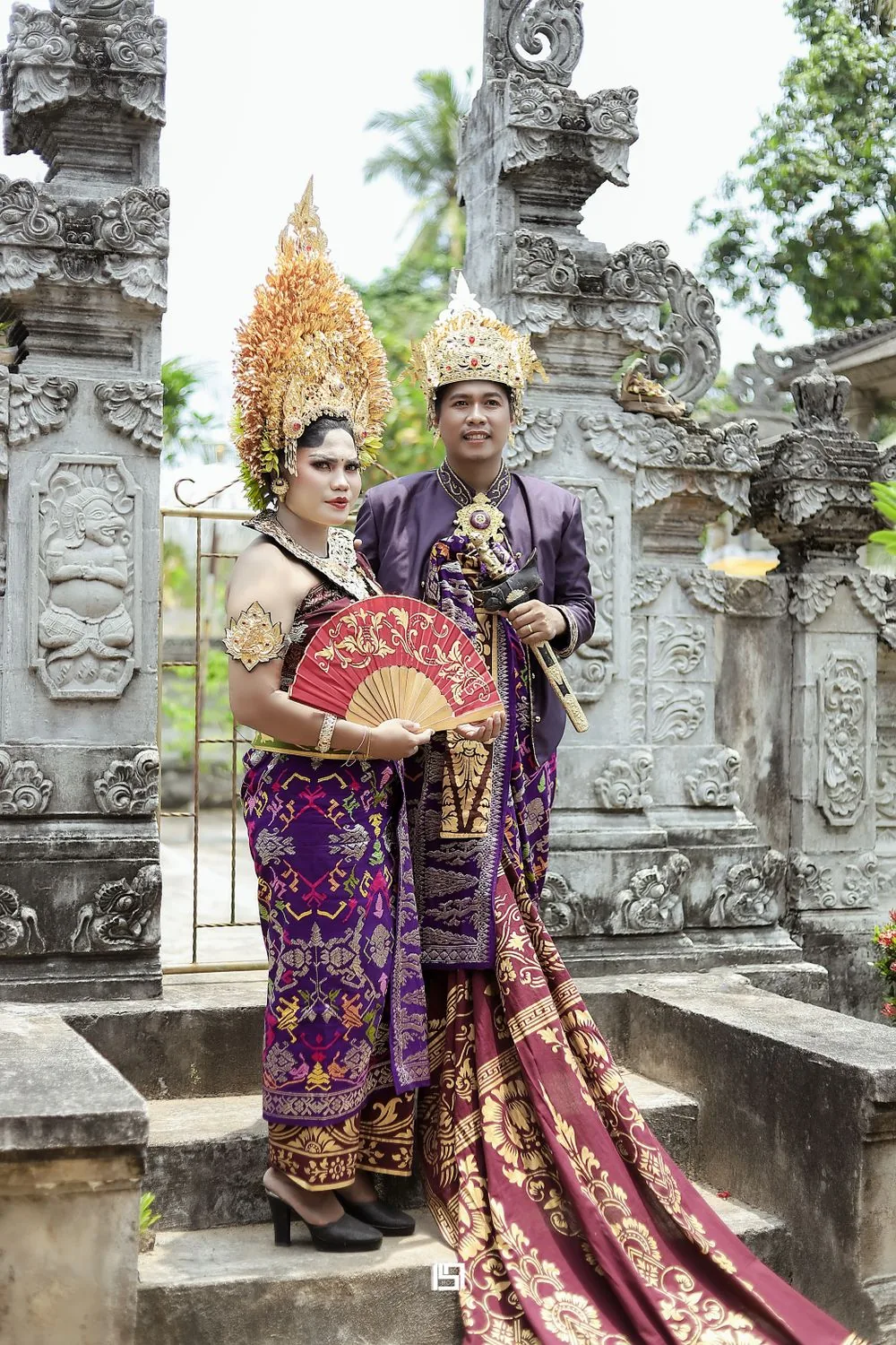 Pasangan Bali dalam busana ungu di gerbang pura