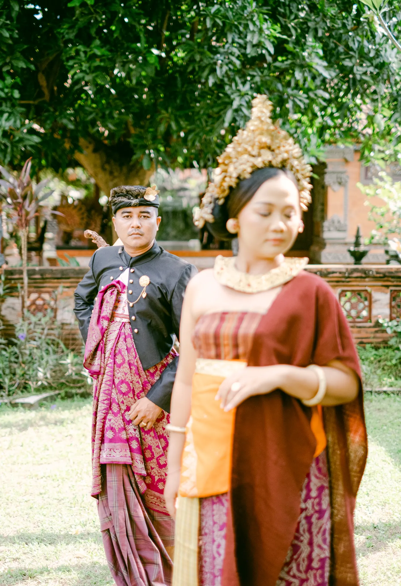 Pasangan dalam busana Bali di halaman hijau