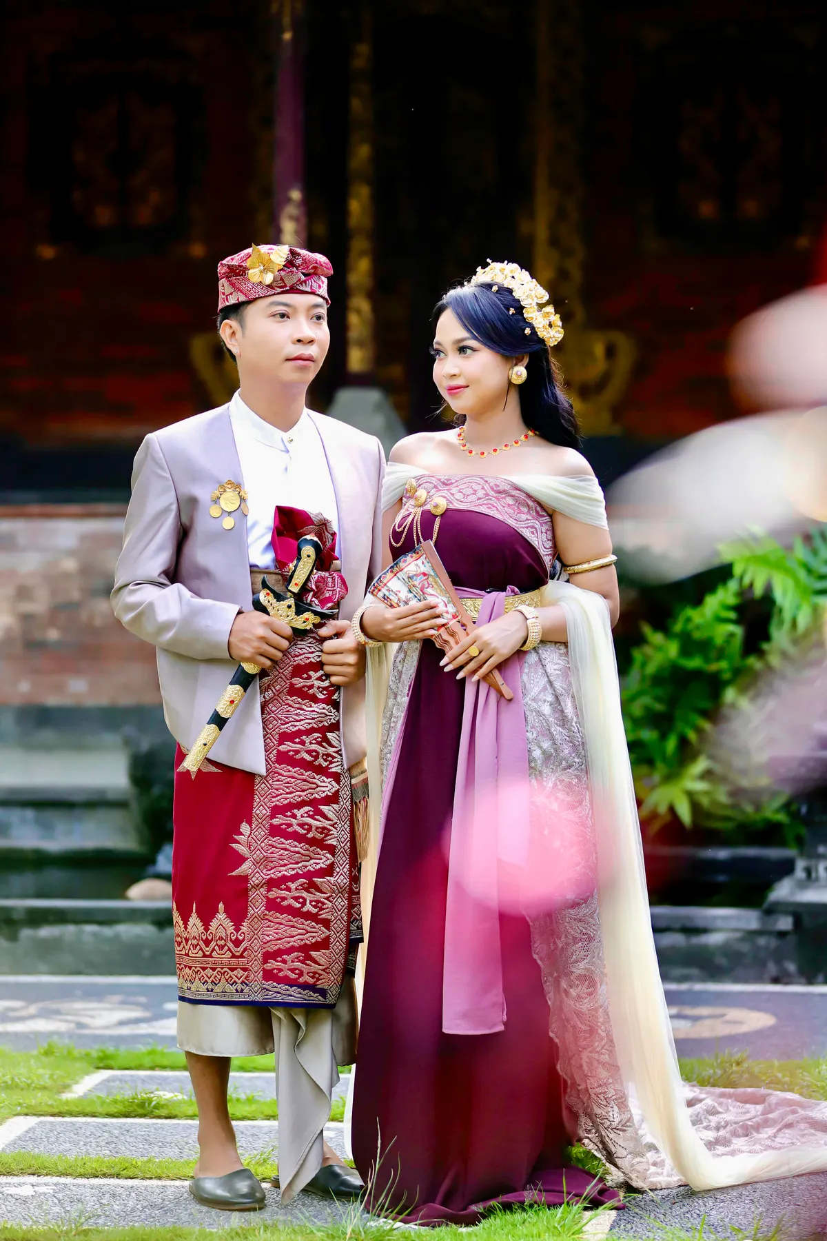 Pasangan berdiri dalam busana pawiwahan Bali