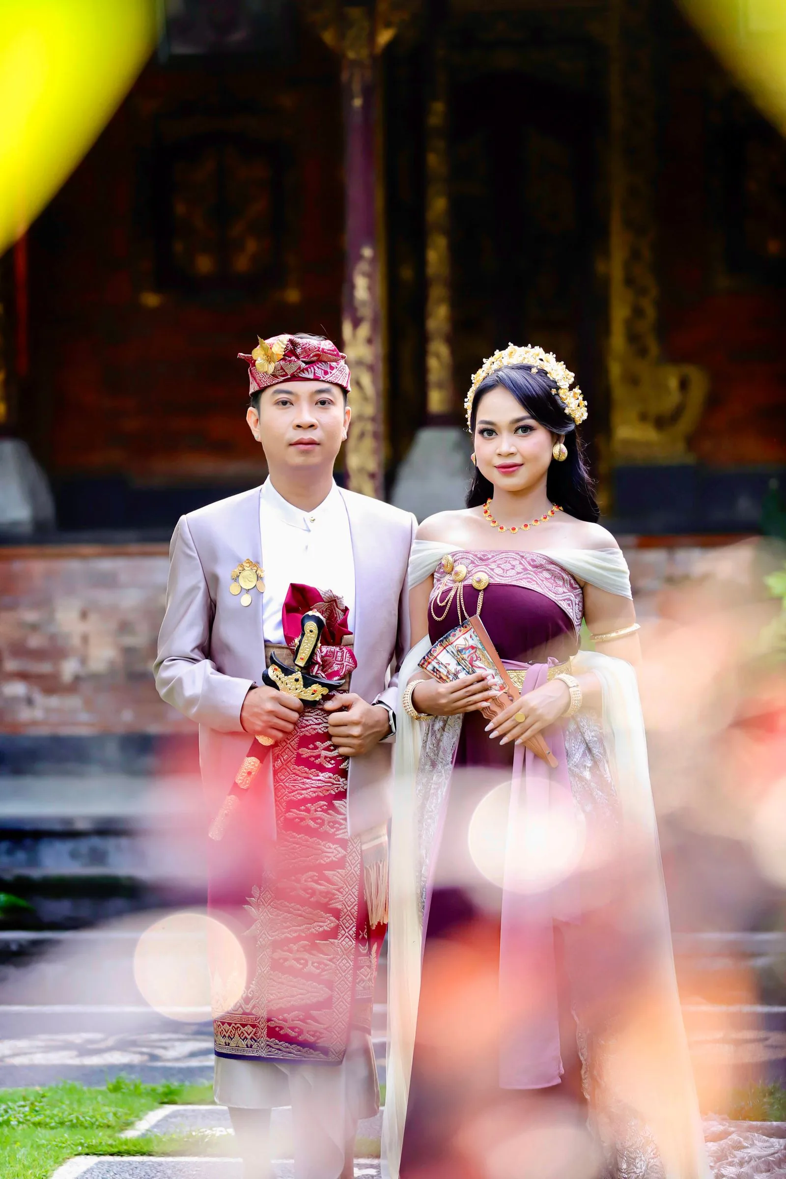 Pasangan Bali berdiri di halaman tradisional
