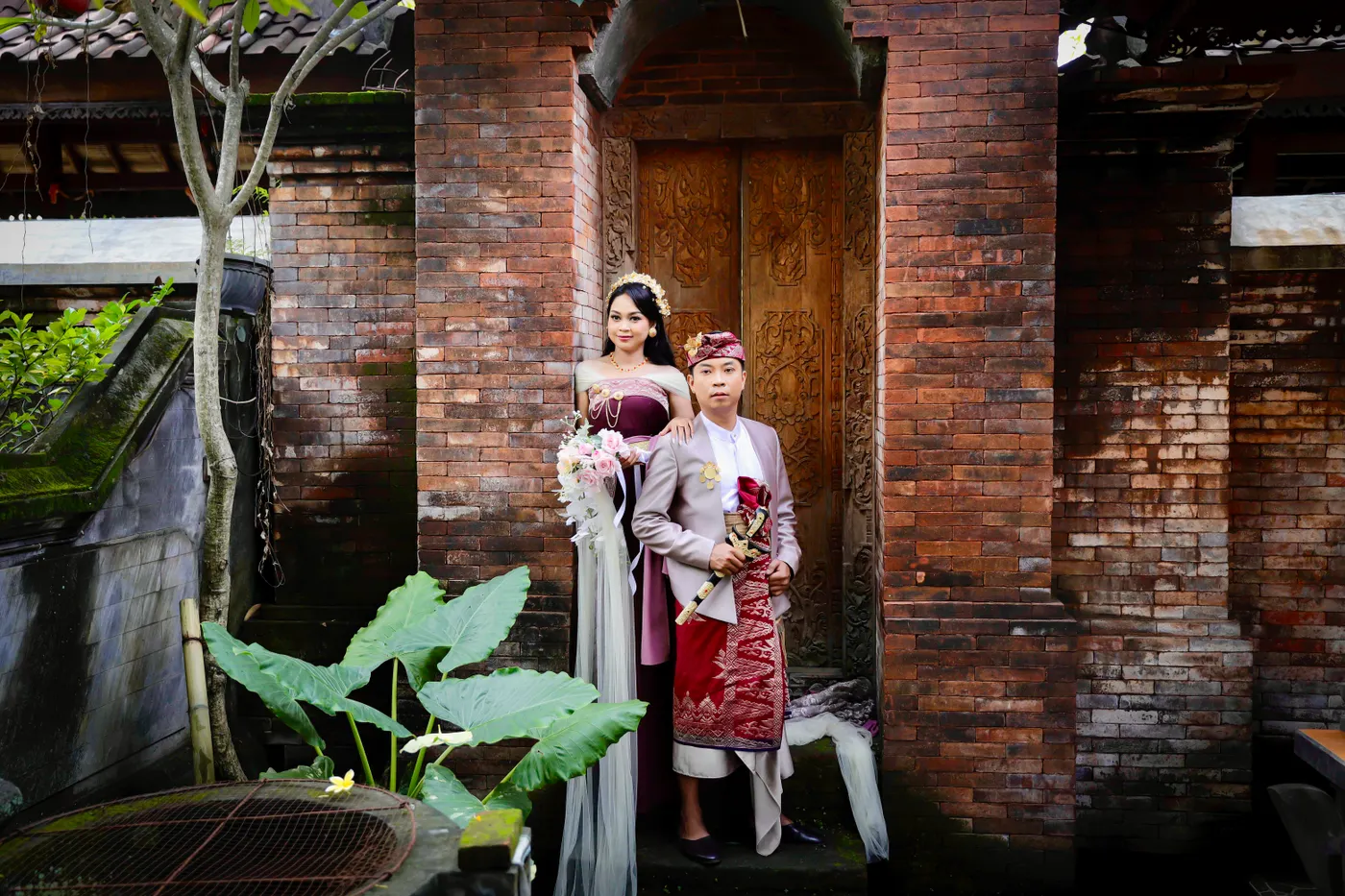 Pasangan berdiri di gerbang rumah Bali